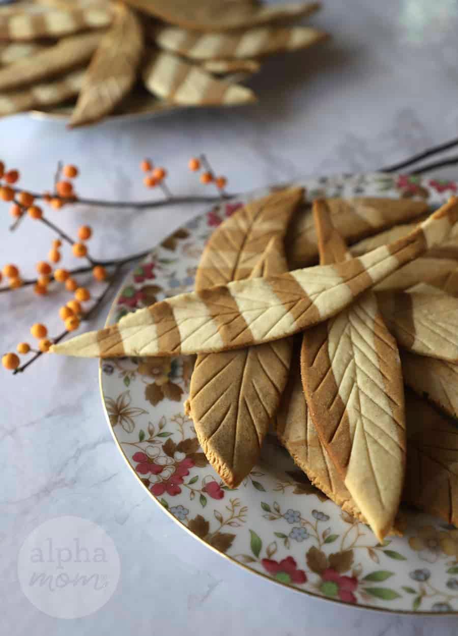 Close-up of feather-shaped cookies being arranged on a baking sheet