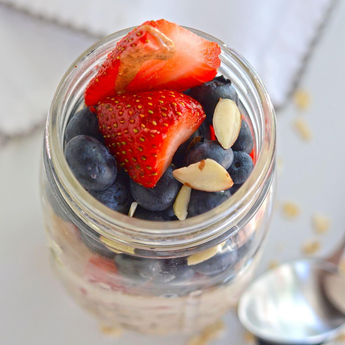 overhead shot of multiple mason jars filled with summer berry swirl overnight oats, garnished with fresh berries and mint