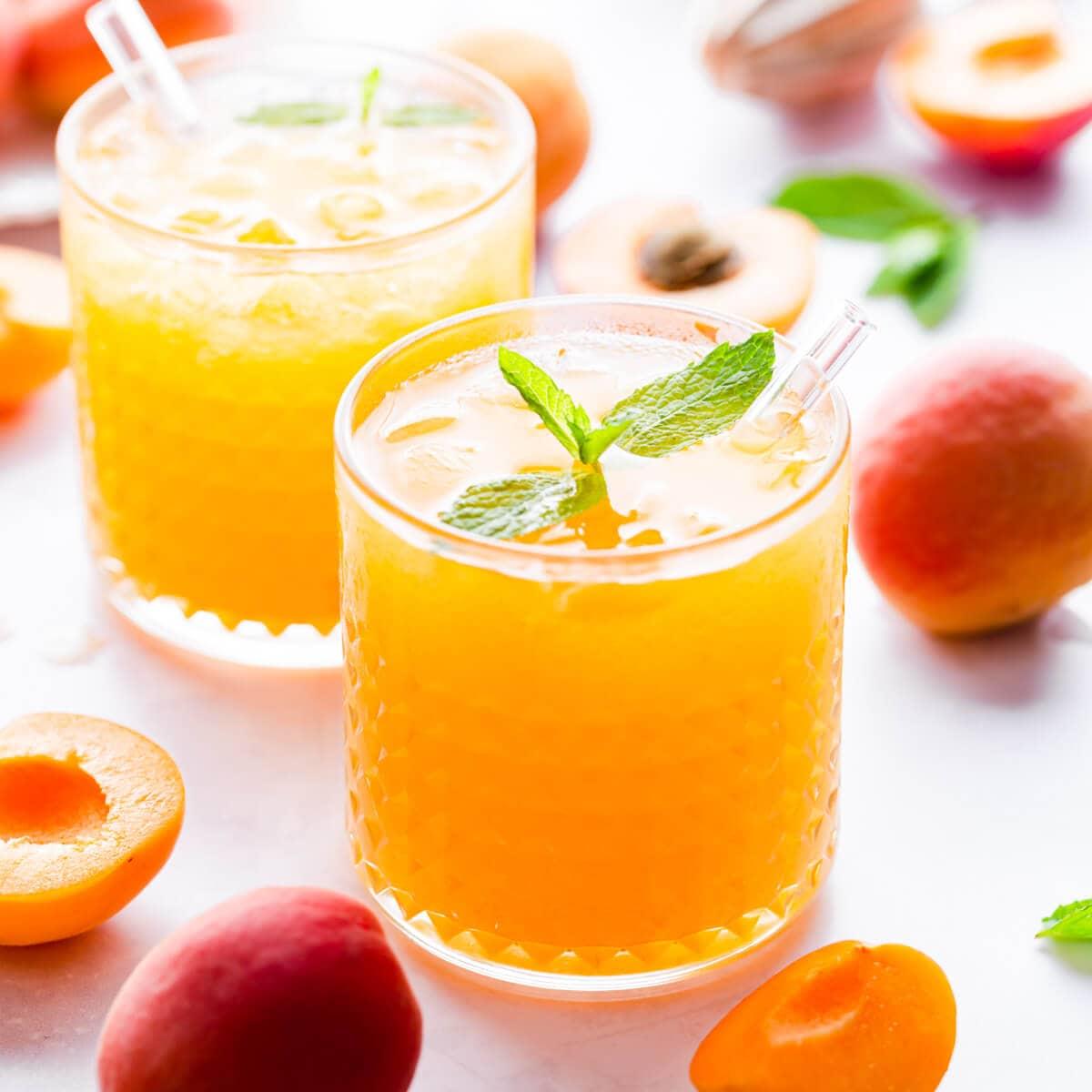 close up of homemade energy nectar in a clear glass with fresh fruits and herbs