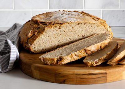 a rustic kitchen scene with a loaf of rhubarb rye bread on a wooden table
