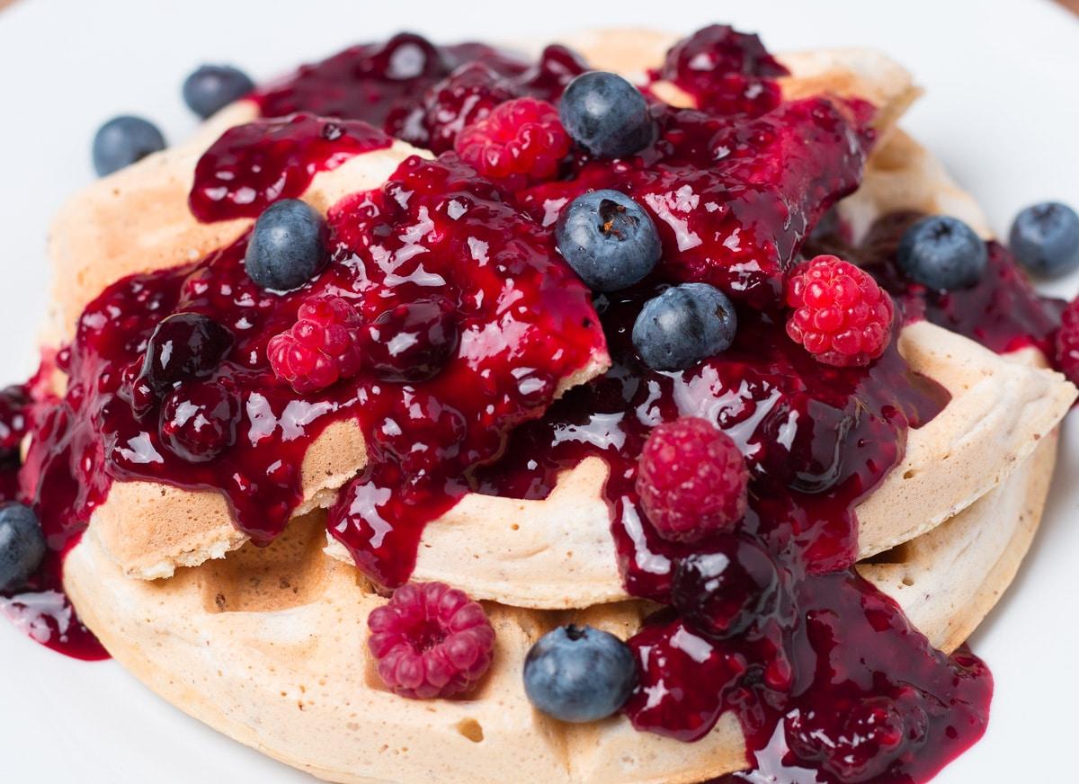 Overhead shot of berry waffle parfaits with various toppings like mint leaves and berry sauce