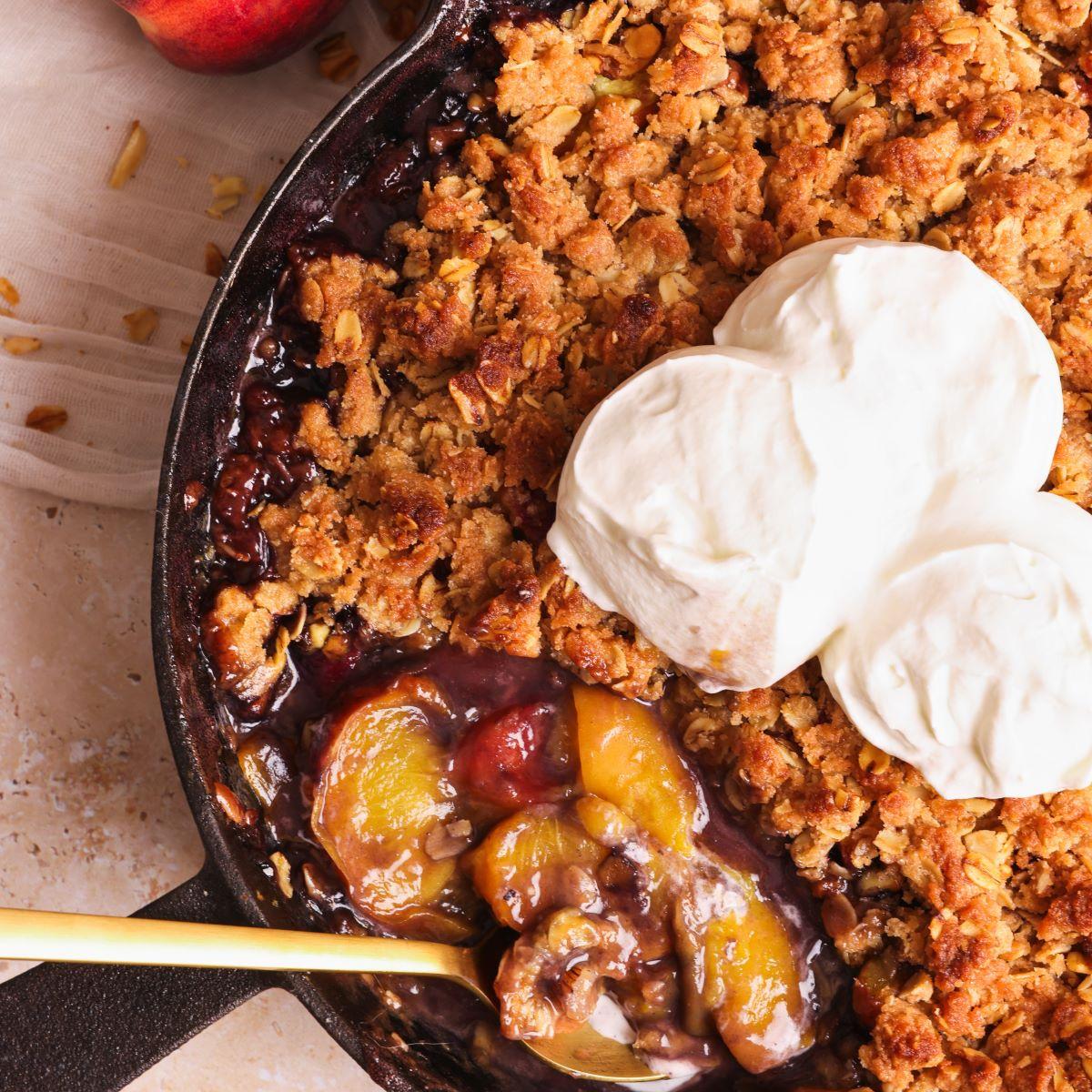 warm peach cobbler with cinnamon crumble topping served in a rustic setting