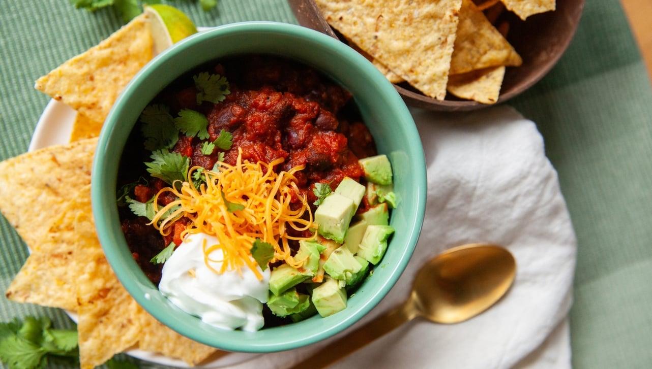 various toppings for chili, such as avocado, cilantro, and sour cream