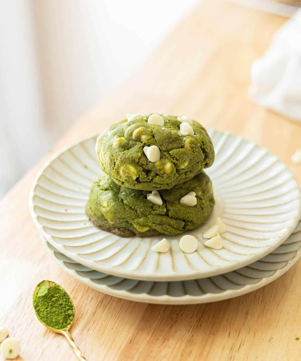 A batch of freshly baked matcha white chocolate gluten-free cookies on a rustic wooden table