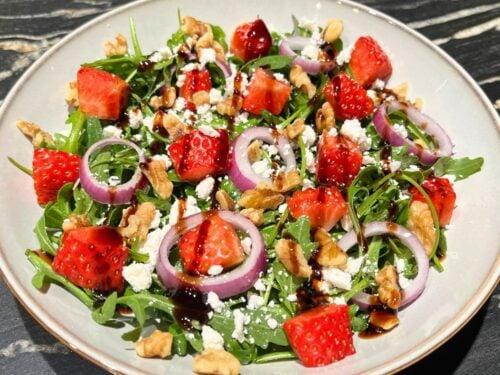 Rubidium Radiance Strawberry Feta Salad on a white plate with a balsamic glaze drizzle