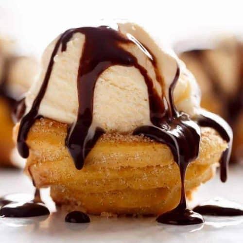 Mini churro bowls filled with vanilla ice cream, drizzled with chocolate sauce