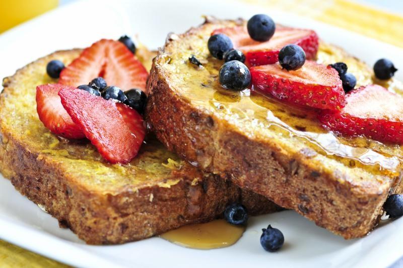 Close-up shot of a slice of Grand Marnier Rhubarb French Toast Bread, drizzled with syrup and garnished with fresh berries
