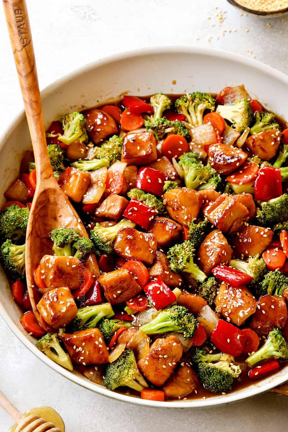 a close-up shot of honey garlic chicken and quinoa stir fry being cooked in a wok