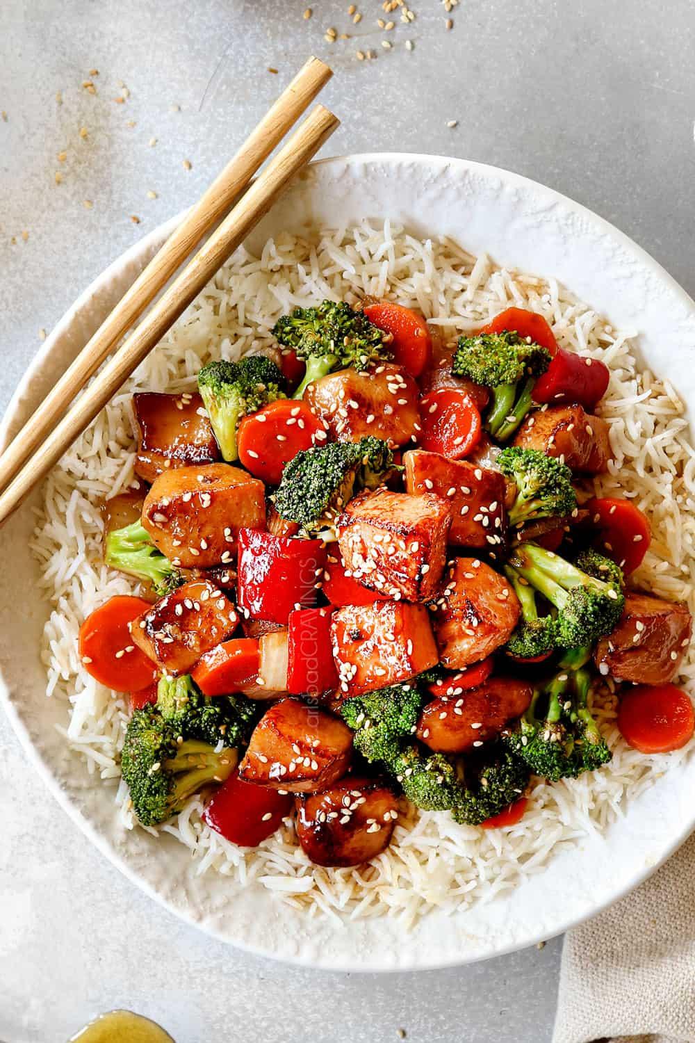 a colorful bowl of honey garlic chicken and quinoa stir fry with steam rising from it
