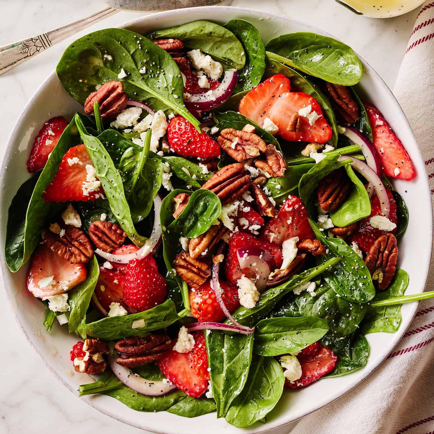 angled shot of strawberry spinach salad with marjoram flowers