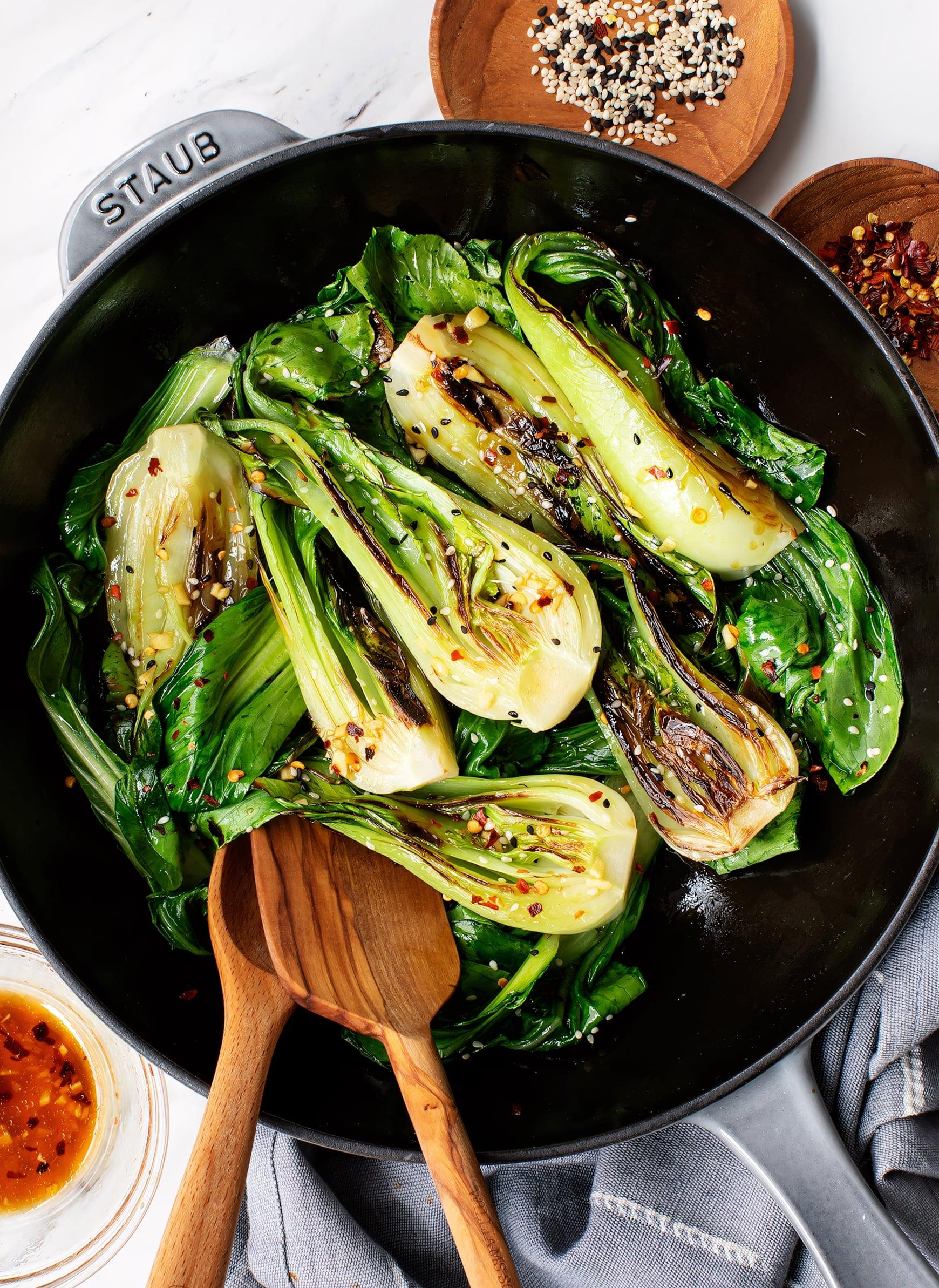 close-up of zucchini and bok choy sauteing in a skillet with garlic.