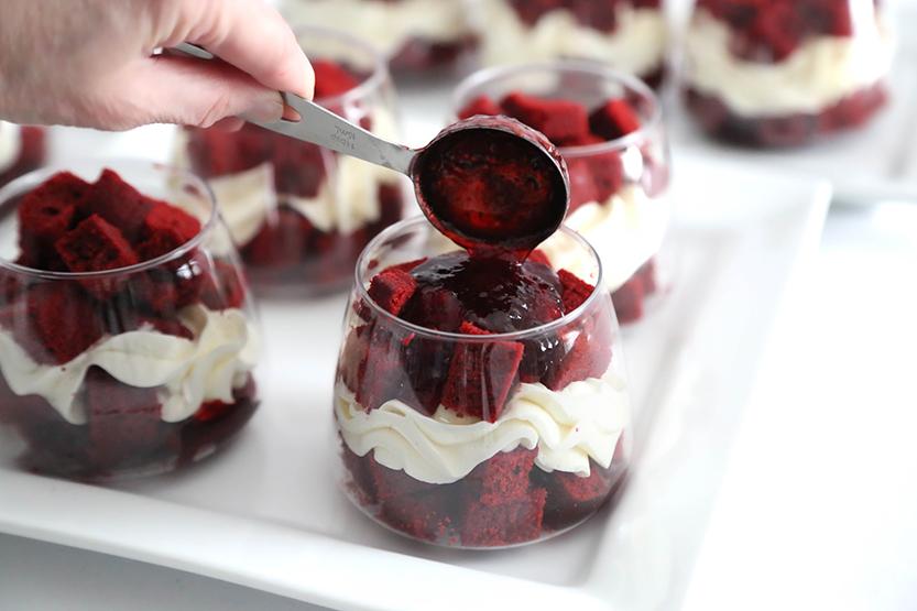 Overhead shot of the 'Velvet Crimson Nightfall' dessert being assembled, showcasing the layers of chocolate pudding and sliced strawberries.