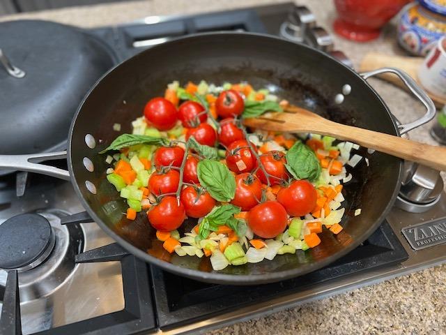 A chef adding cherries to a pan of risotto.
