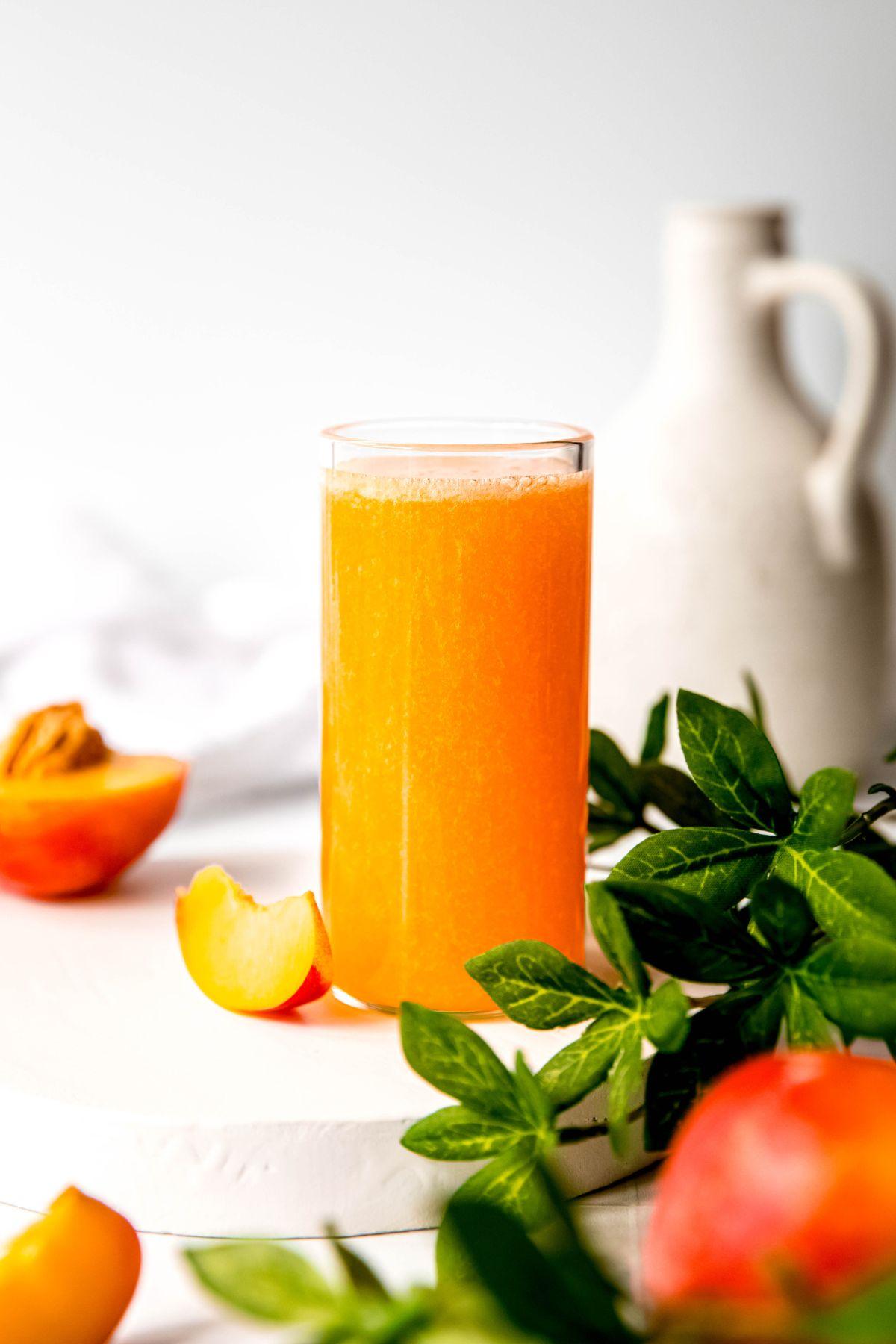 A top-down shot of the ingredients laid out on a wooden cutting board before being blended: fresh strawberries, a peeled mango, a bottle of orange juice, and a jar of honey.
