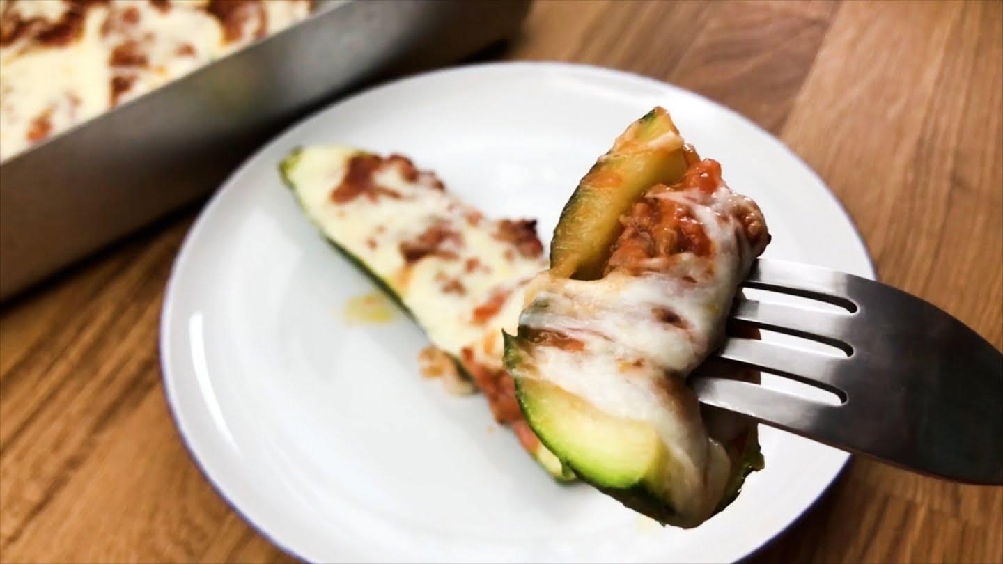 A person serving a stuffed zucchini half on a plate