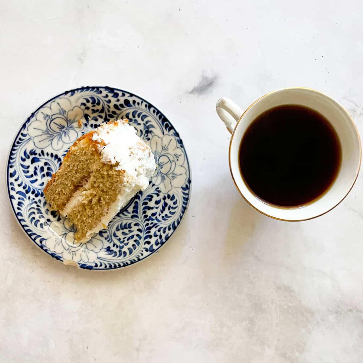 slice of rhubarb cake on a plate next to a cup of tea