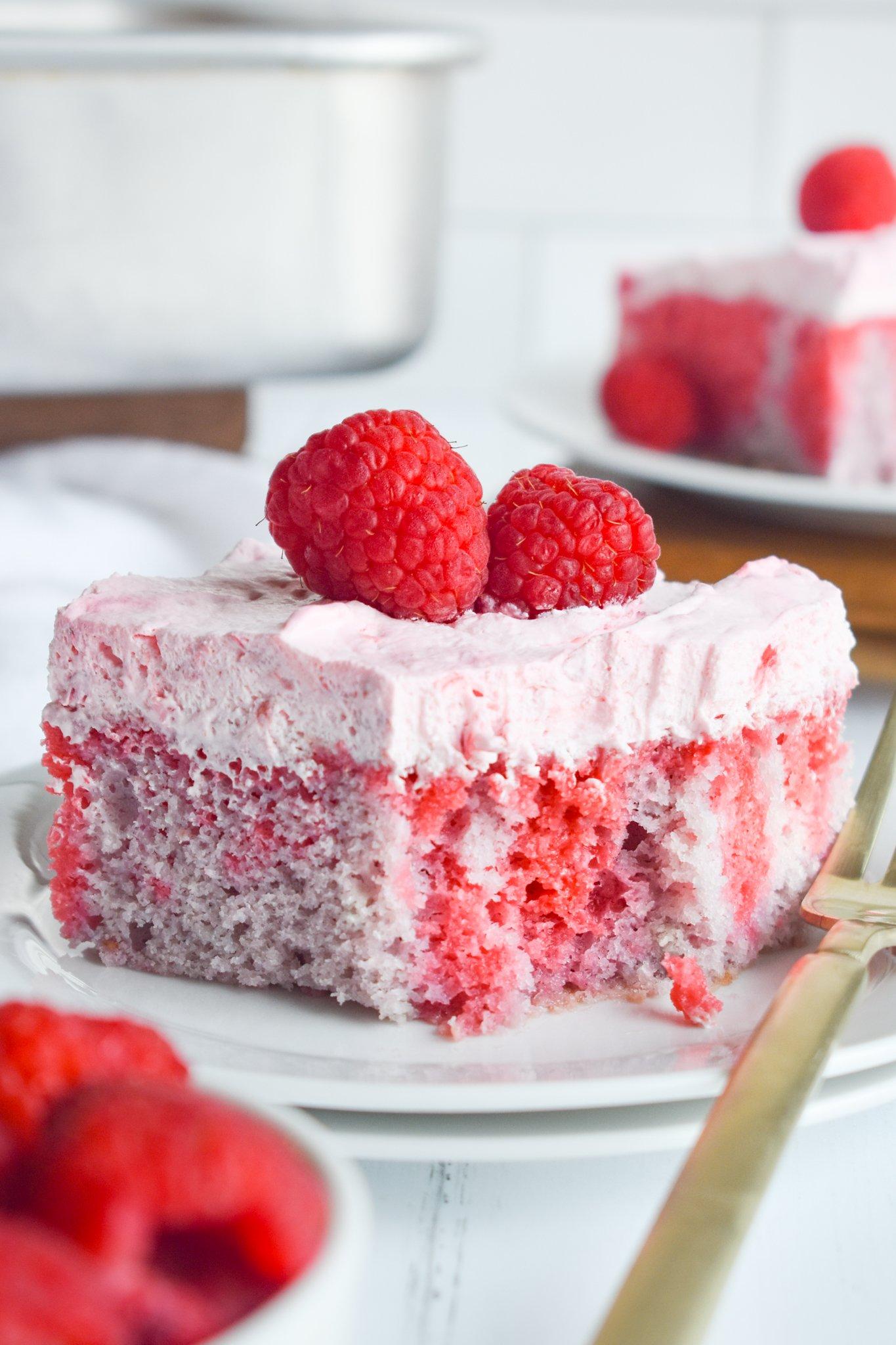 woman adding raspberries to cake batter in a bright kitchen
