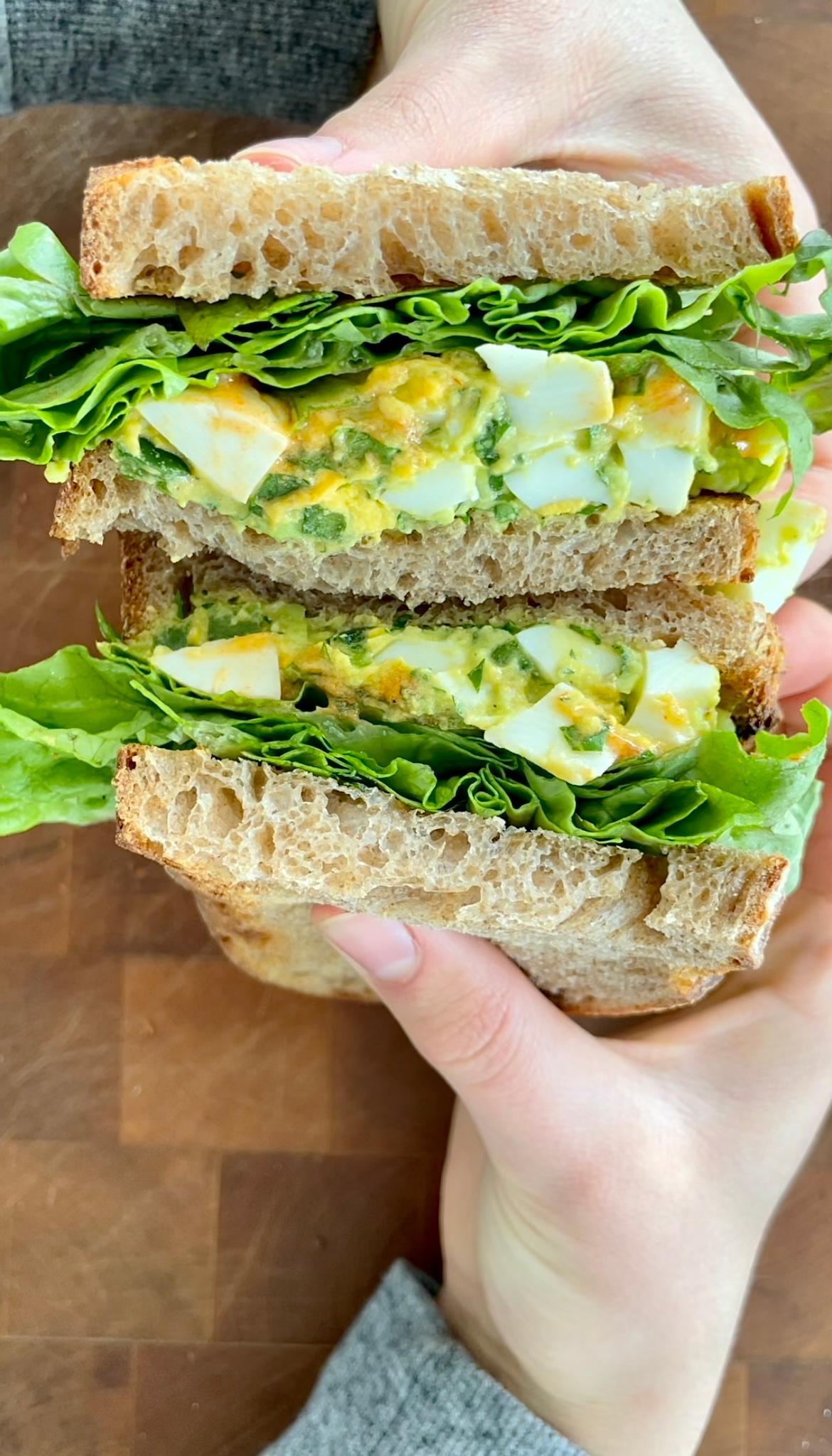 avocado and egg salad sandwich cut in half, showing the filling