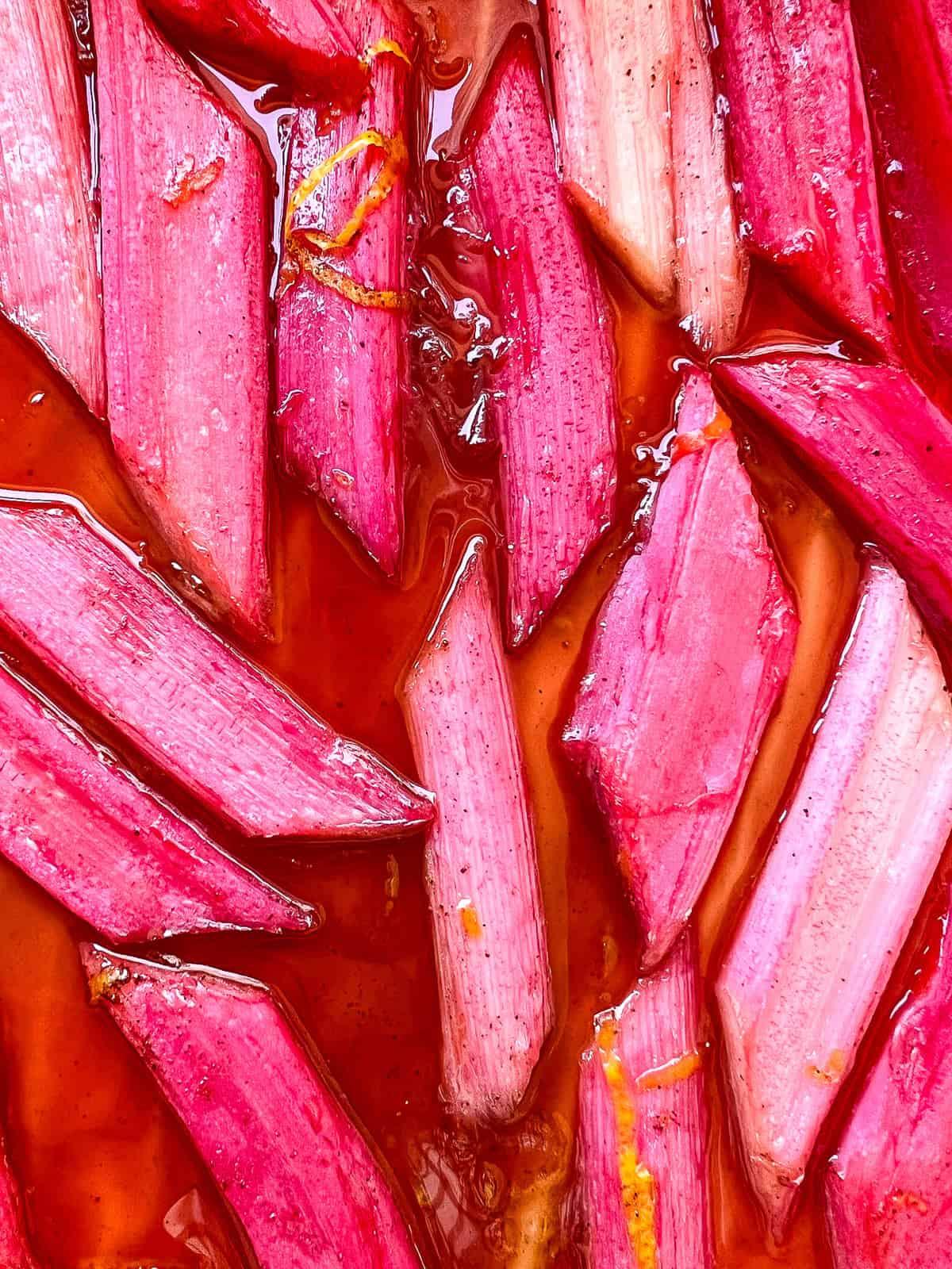 close up shot of rhubarb stalks with vibrant pink and green hues, some stalks are cut into small pieces ready for baking