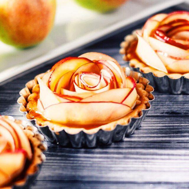 The whole salted caramel apple rose tart on a rustic wooden table with a warm, inviting background