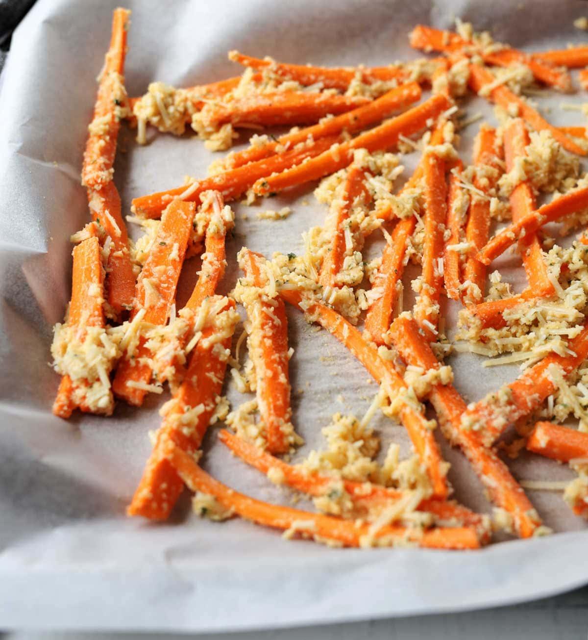 close up shot of honey garlic parmesan carrot fries on a baking sheet