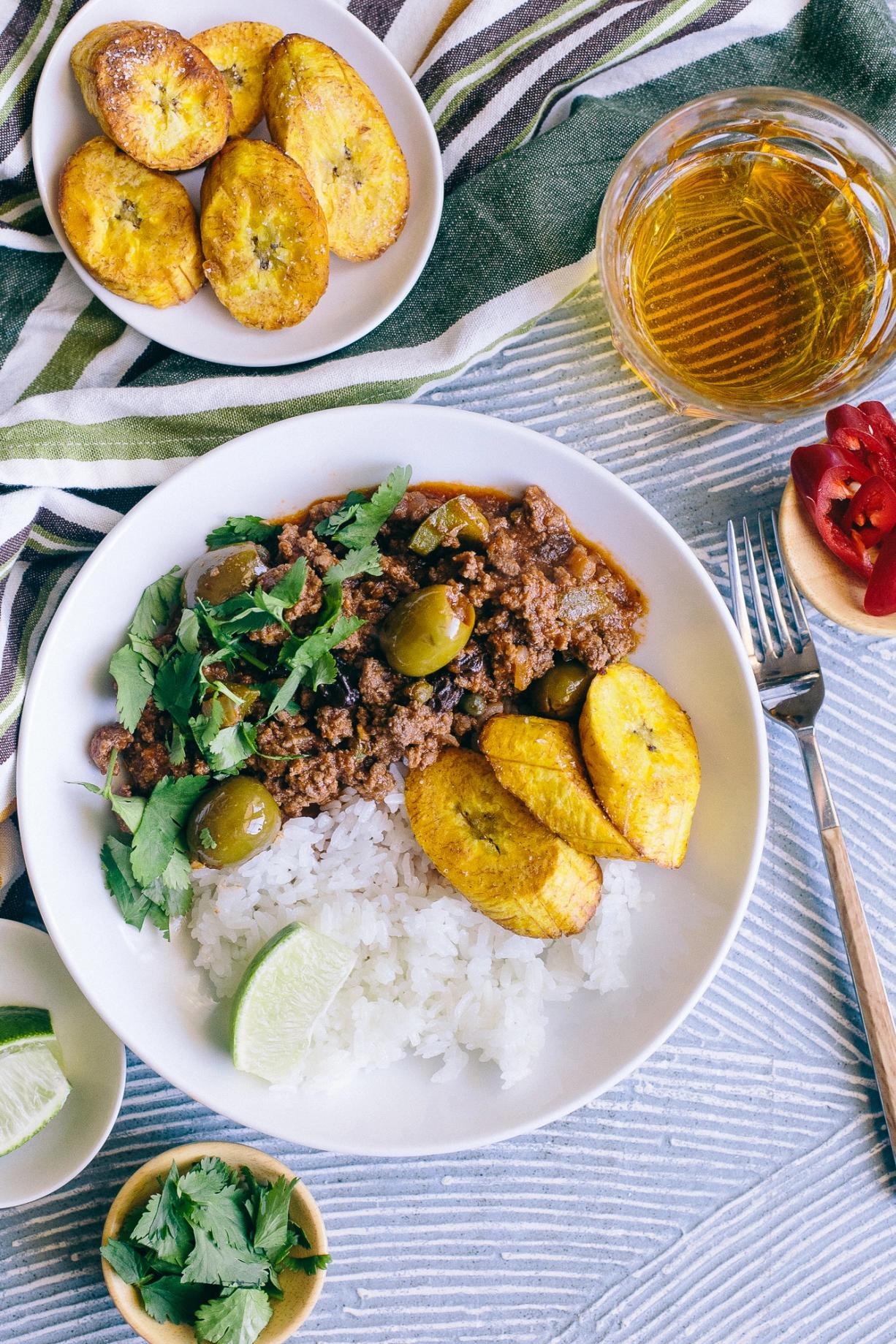 Close-up shot of picadillo being served over a bed of fluffy white rice, garnished with fresh cilantro