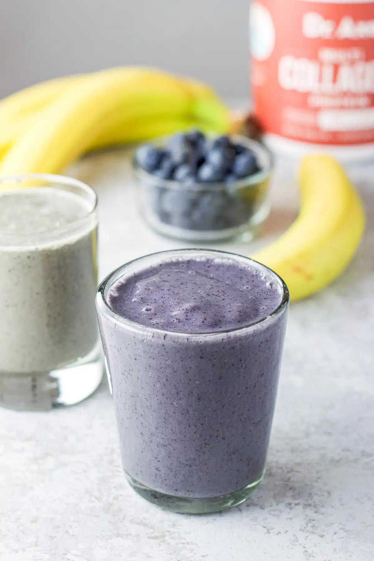 close-up shot of ingredients for a berry spinach smoothie: spinach, berries, banana, almond milk