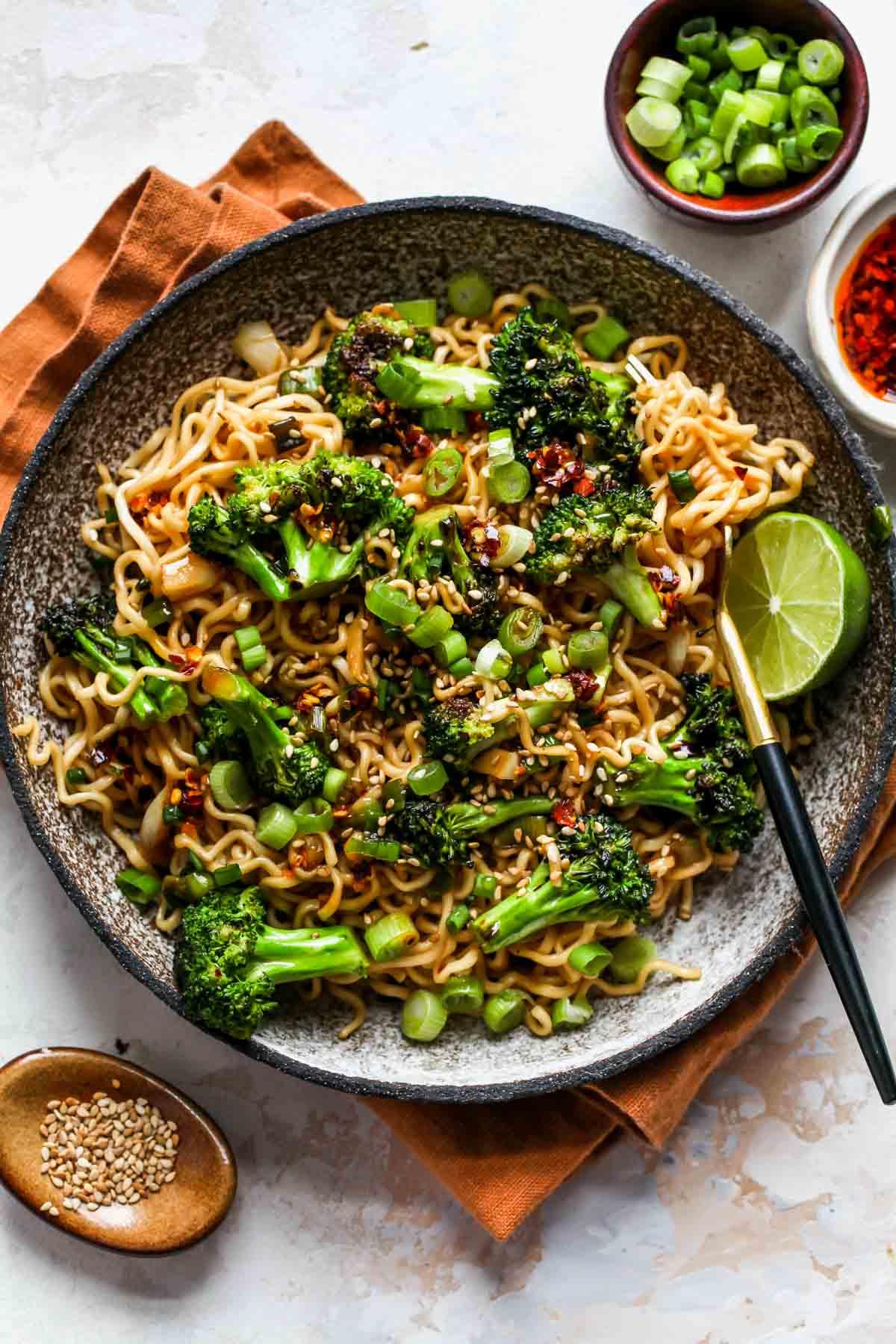 Overhead view of a bowl of ginger scallion beef stir-fry noodles, garnished with sesame seeds and scallions