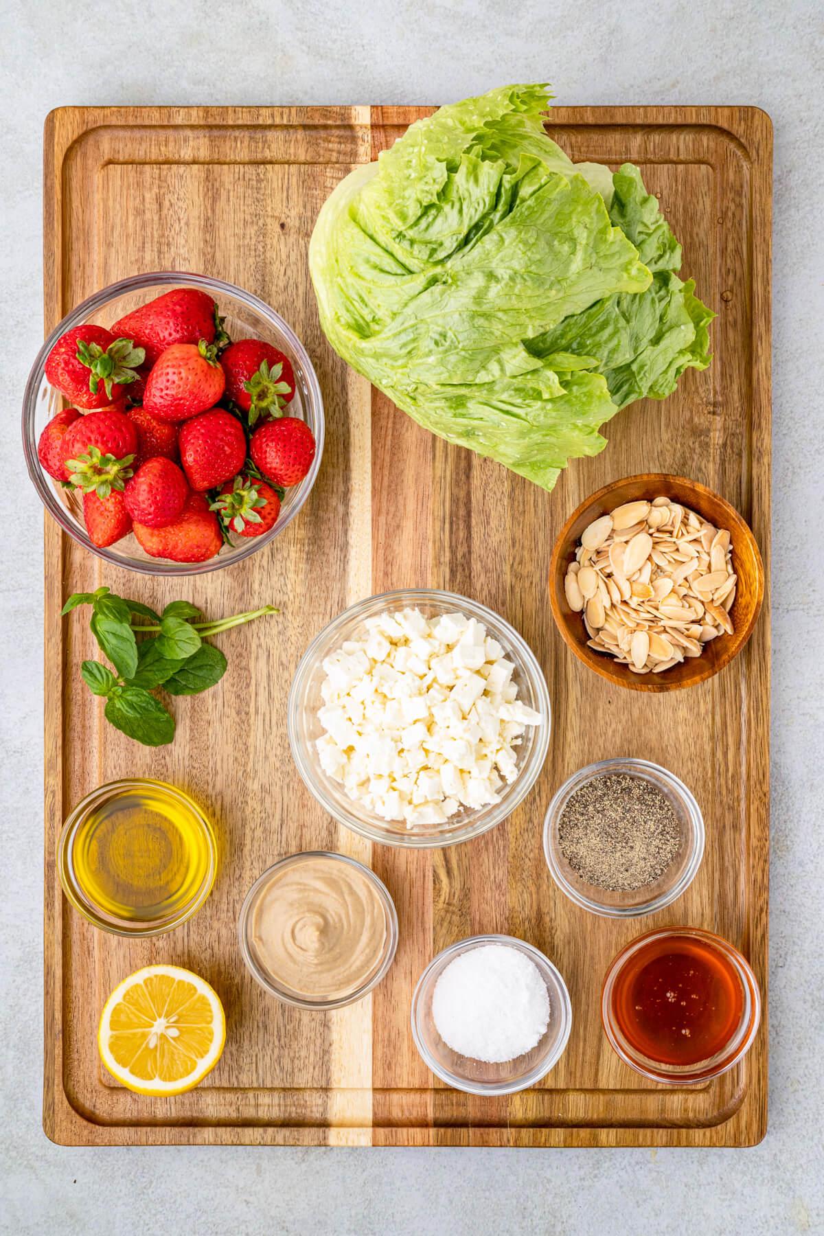 ingredients for strawberry feta salad laid out on a wooden table