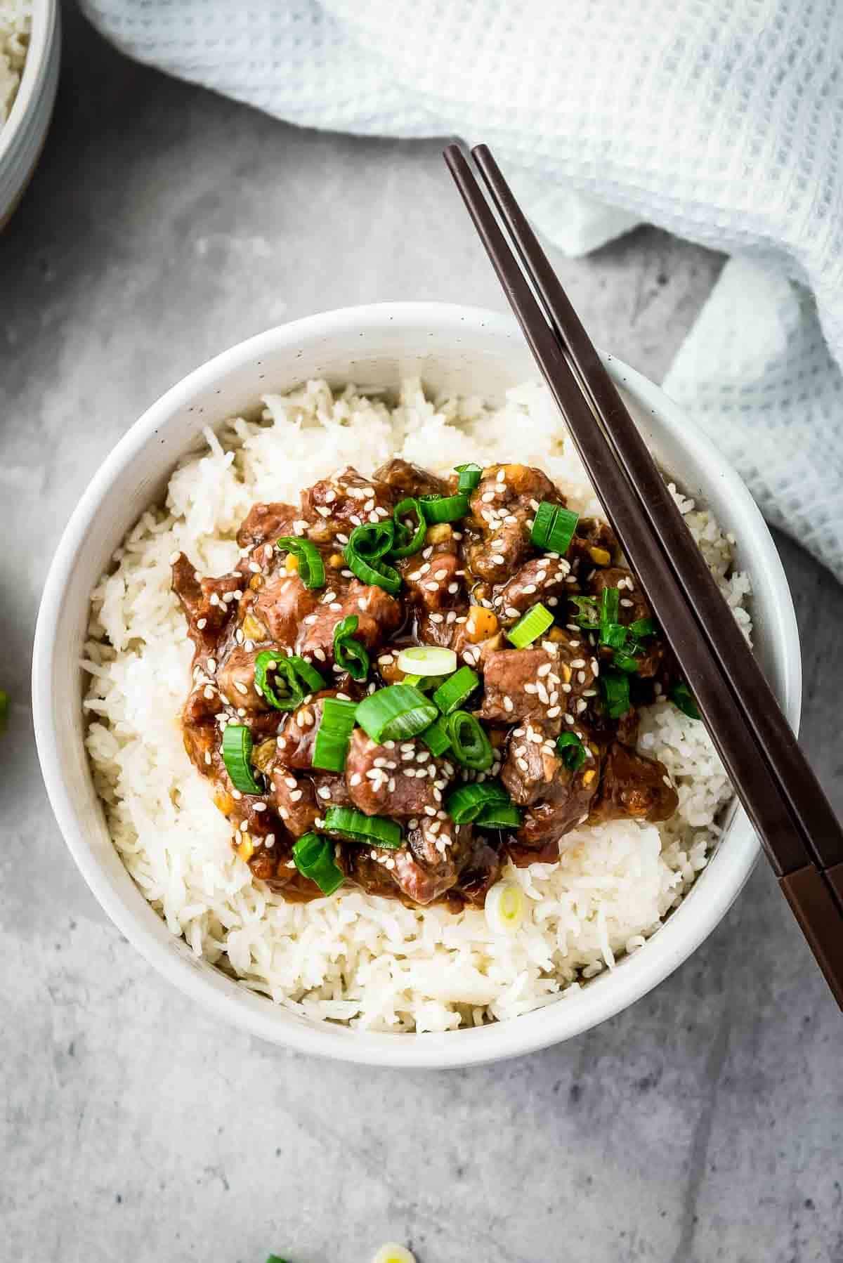 Overhead shot of a completed bowl of Mongolian beef stir-fry with chopsticks