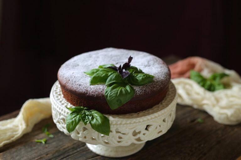 whole basil olive oil chocolate cake decorated with fresh basil leaves