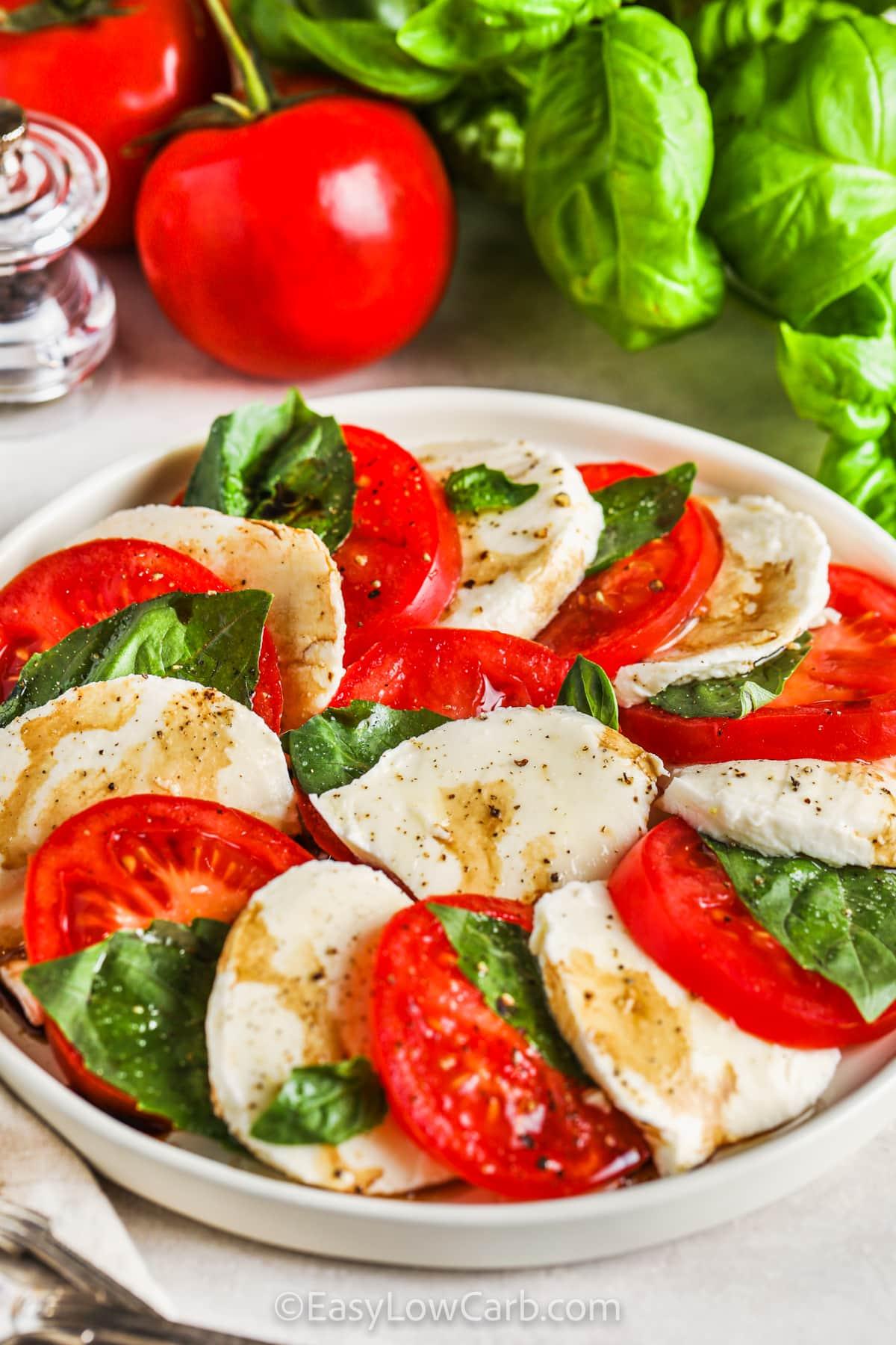 Close-up of a Caprese salad with white balsamic dressing, basil leaves, and vibrant tomatoes