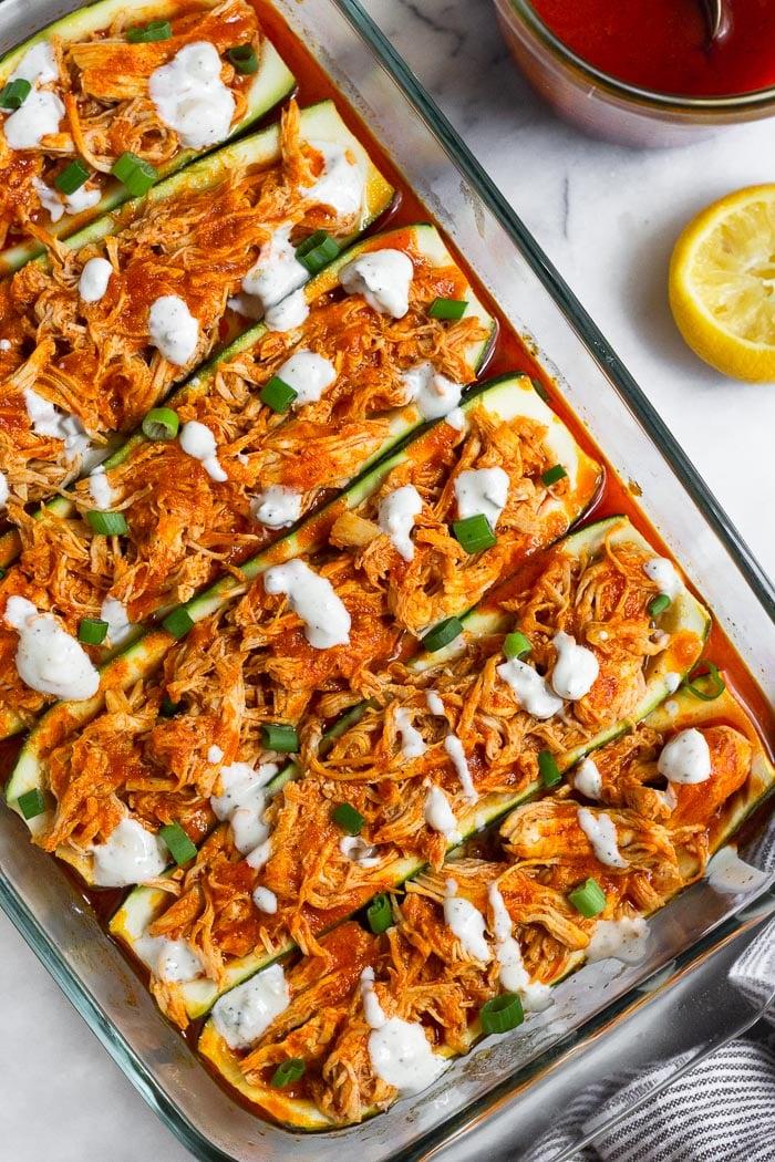 Overhead shot of buffalo chicken stuffed zucchini halves on a baking sheet