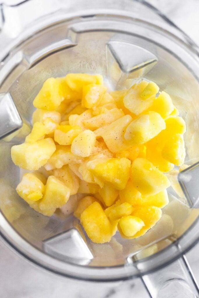 blender filled with pineapple and coconut milk for ice cream