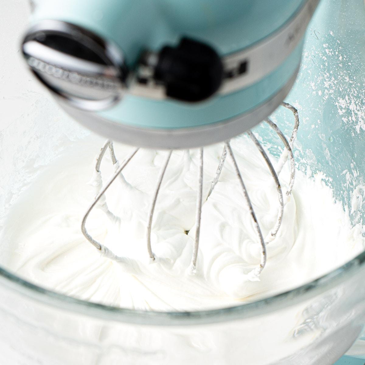 Smooth royal icing being prepared in a stand mixer, glossy texture