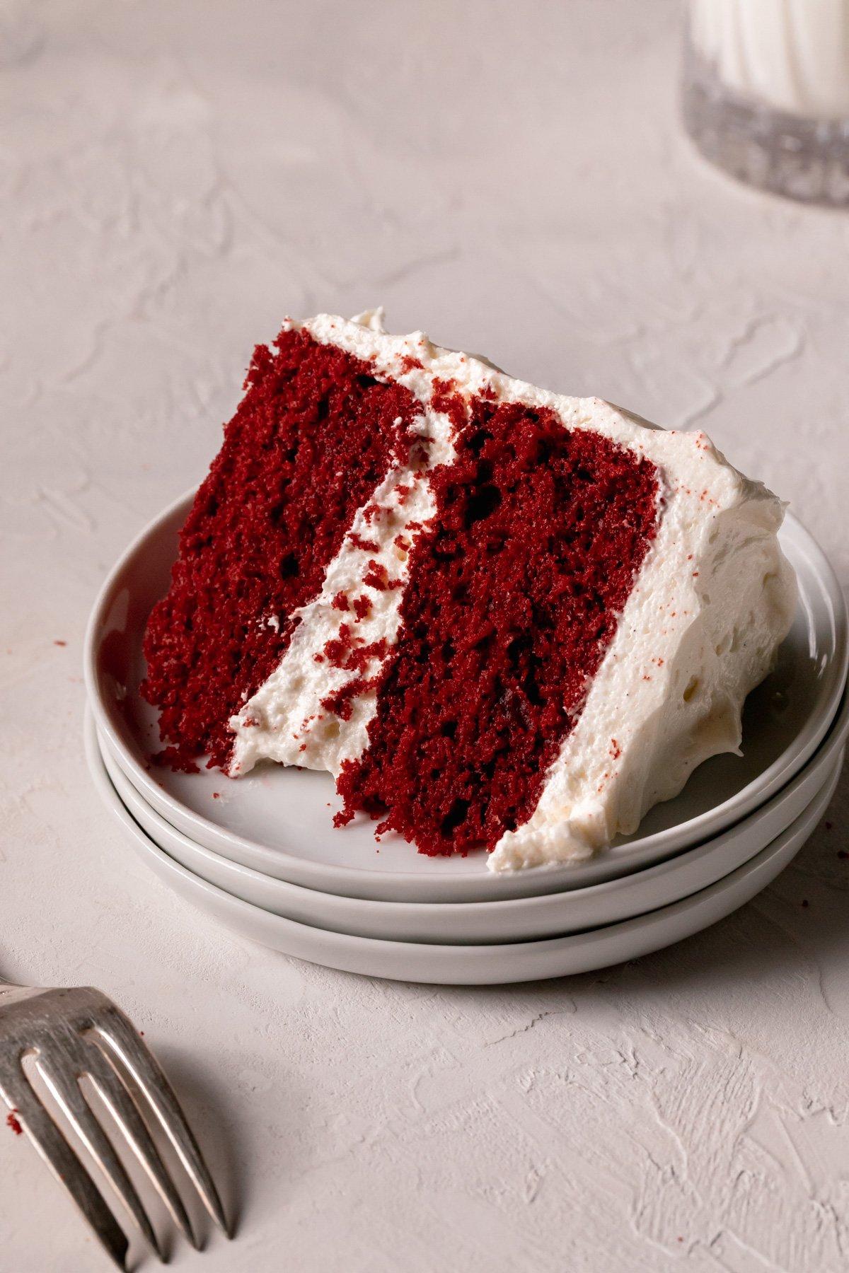 slice of crimson red velvet cake on a white plate with a fork