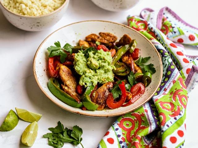 Overhead shot of ingredients for keto chicken fajita bowls laid out on a wooden surface