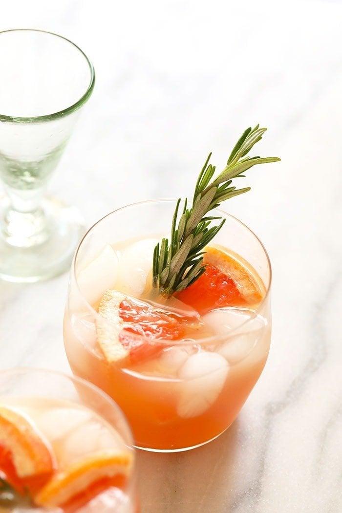 Overhead shot of several Earl Grey Grapefruit Hugo cocktails on a table, garnished with grapefruit peels and rosemary sprigs
