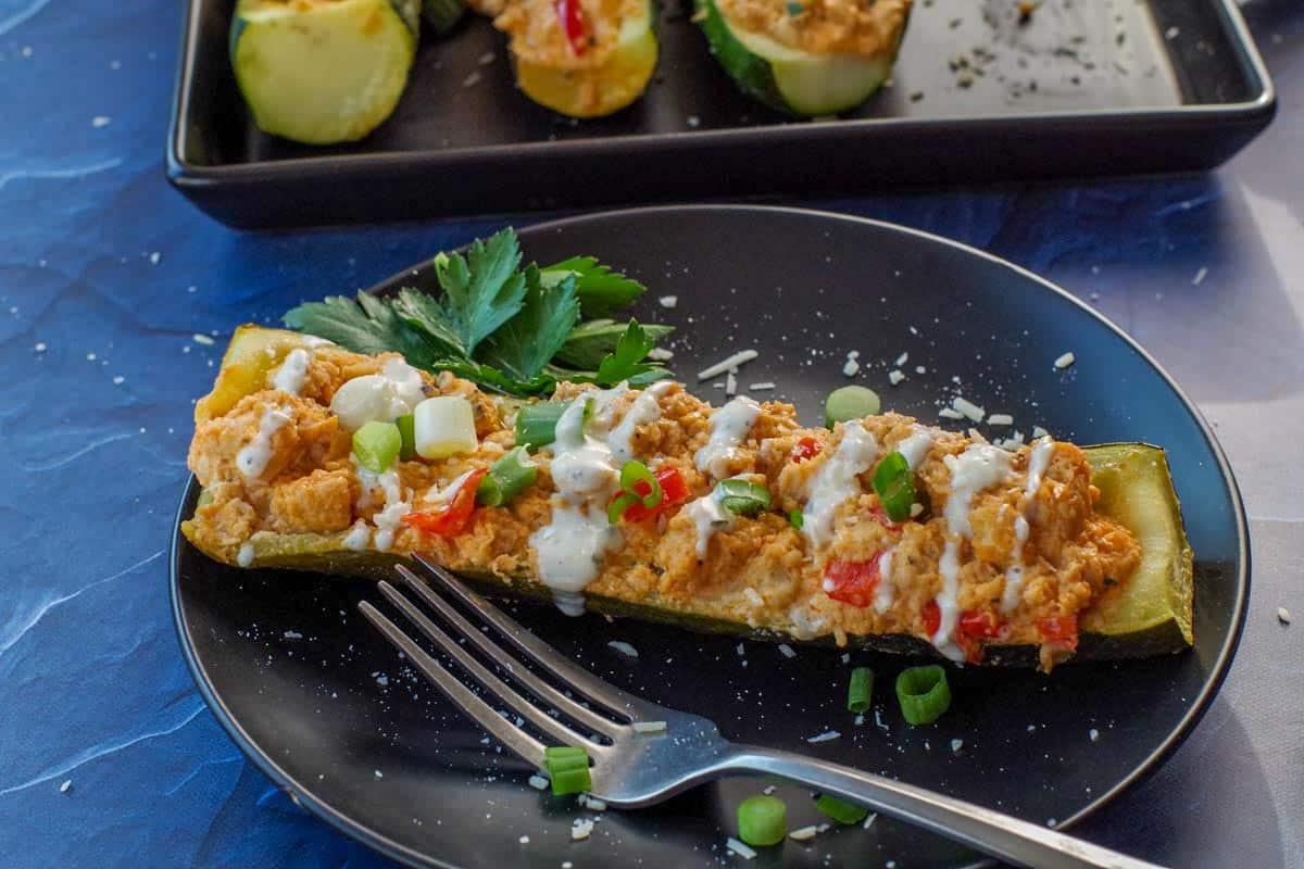 Buffalo chicken stuffed zucchini on a plate with celery sticks