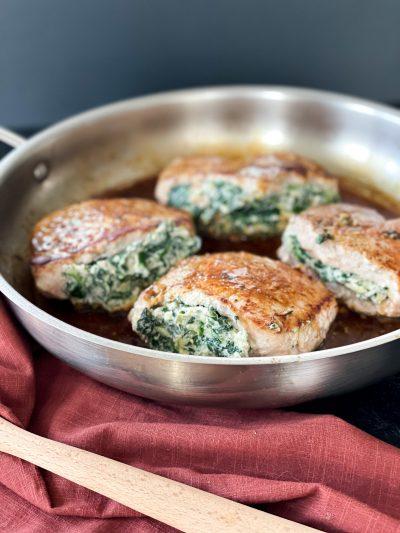 close up shot of spinach and artichoke filling being spooned into a pork chop pocket