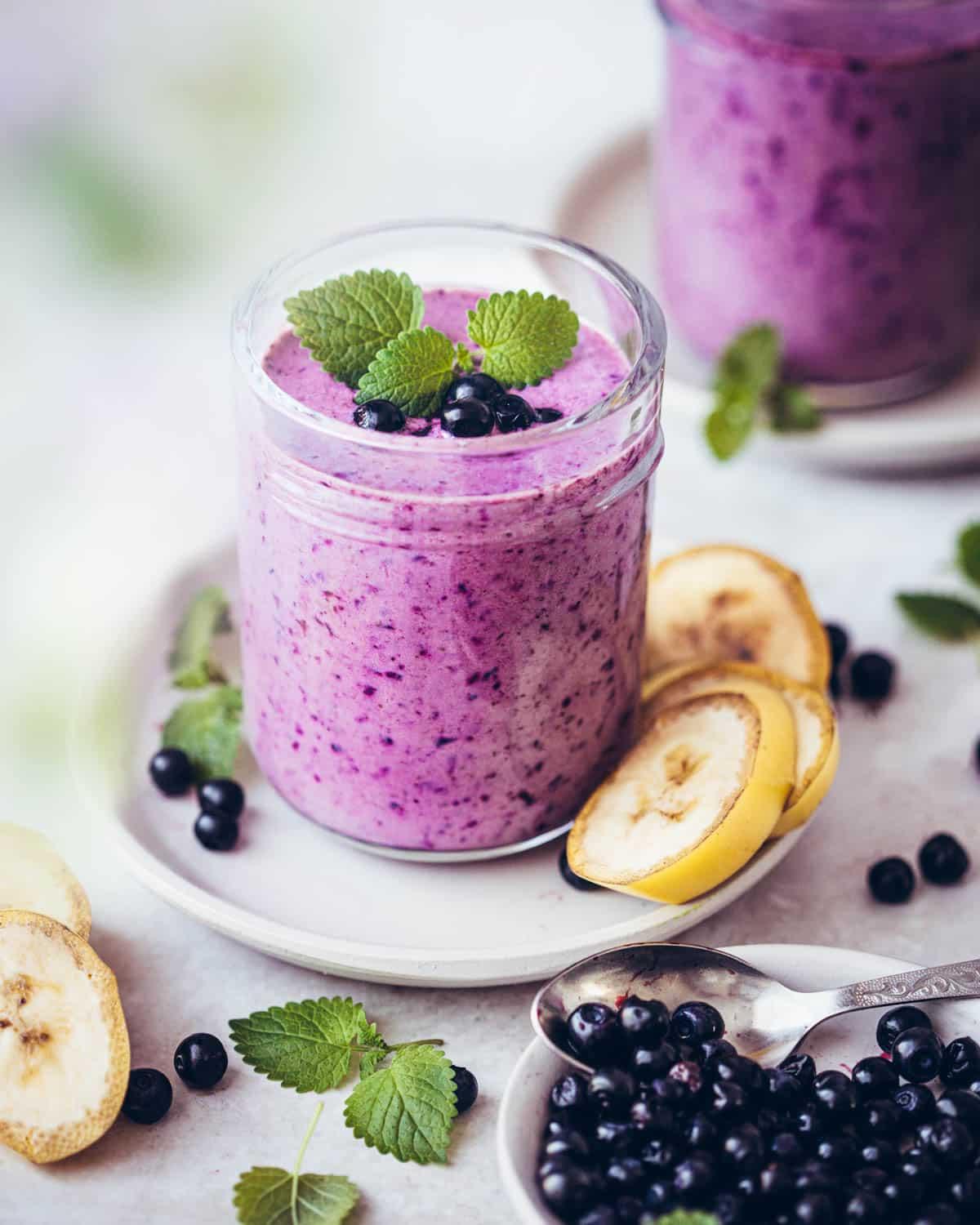 A refreshing berry smoothie in a glass with fresh berries scattered around