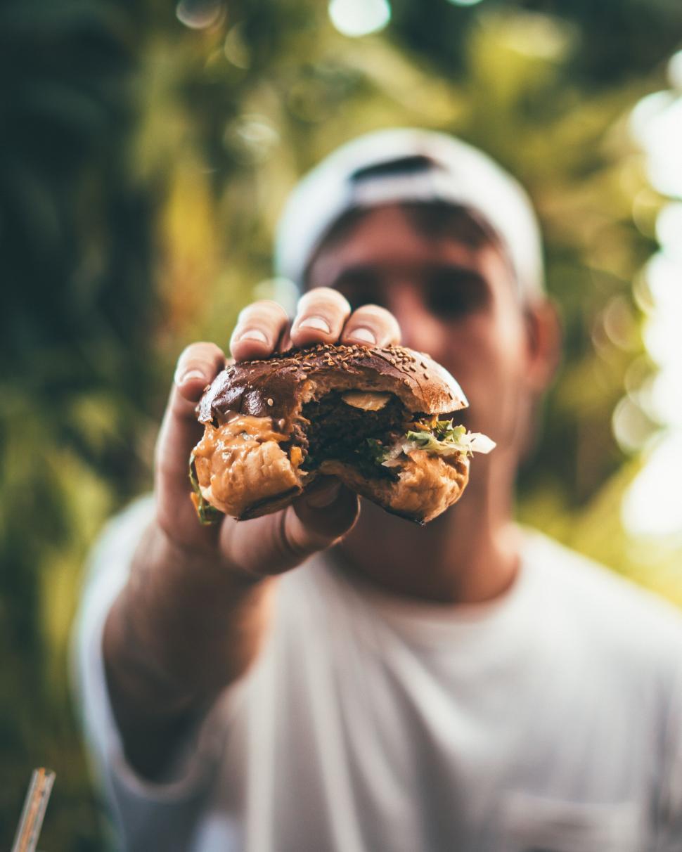 a person holding a rosewater almond ice cream sandwich, about to take a bite