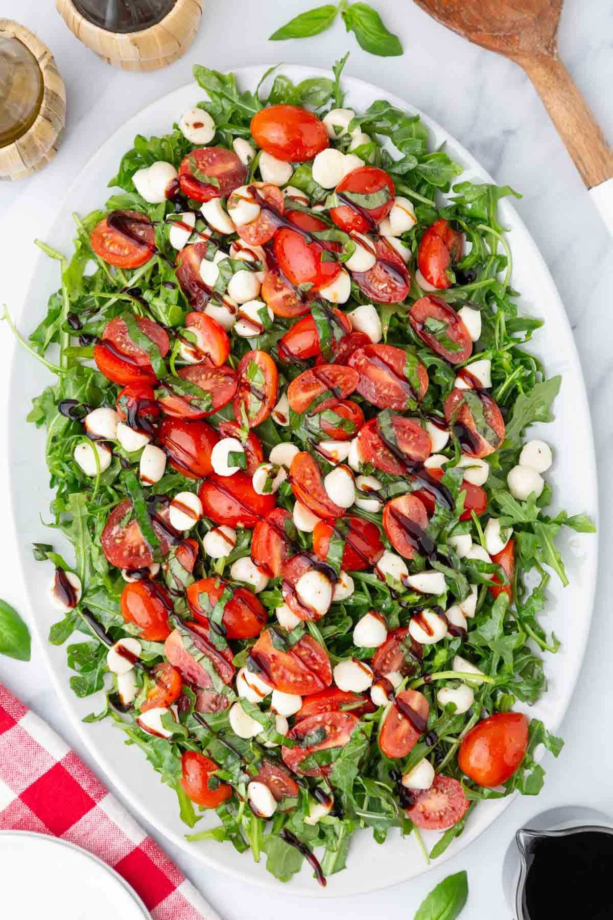 Ingredients for Caprese salad with arugula laid out on a wooden table