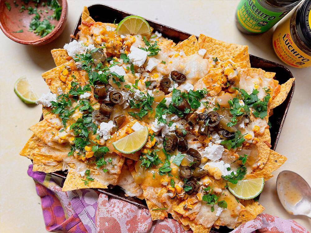 Close-up shot of a single Street Corn Nachos Supreme, showcasing the melted cheese, creamy corn mixture, and fresh toppings