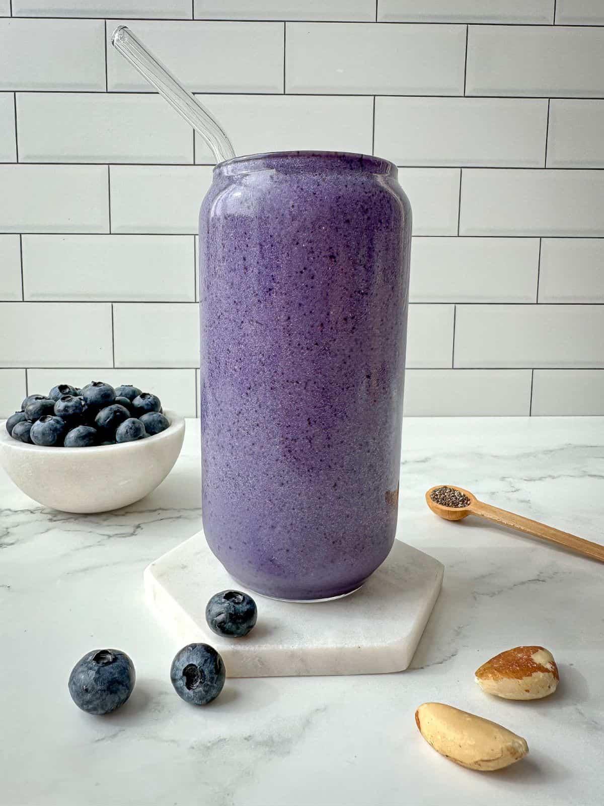 close-up of a vibrant blueberry protein shake in a glass with fresh blueberries and protein powder in the background