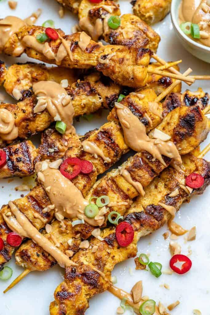 close-up of peanut chicken parmesan satay skewers with dipping sauce drizzled on top