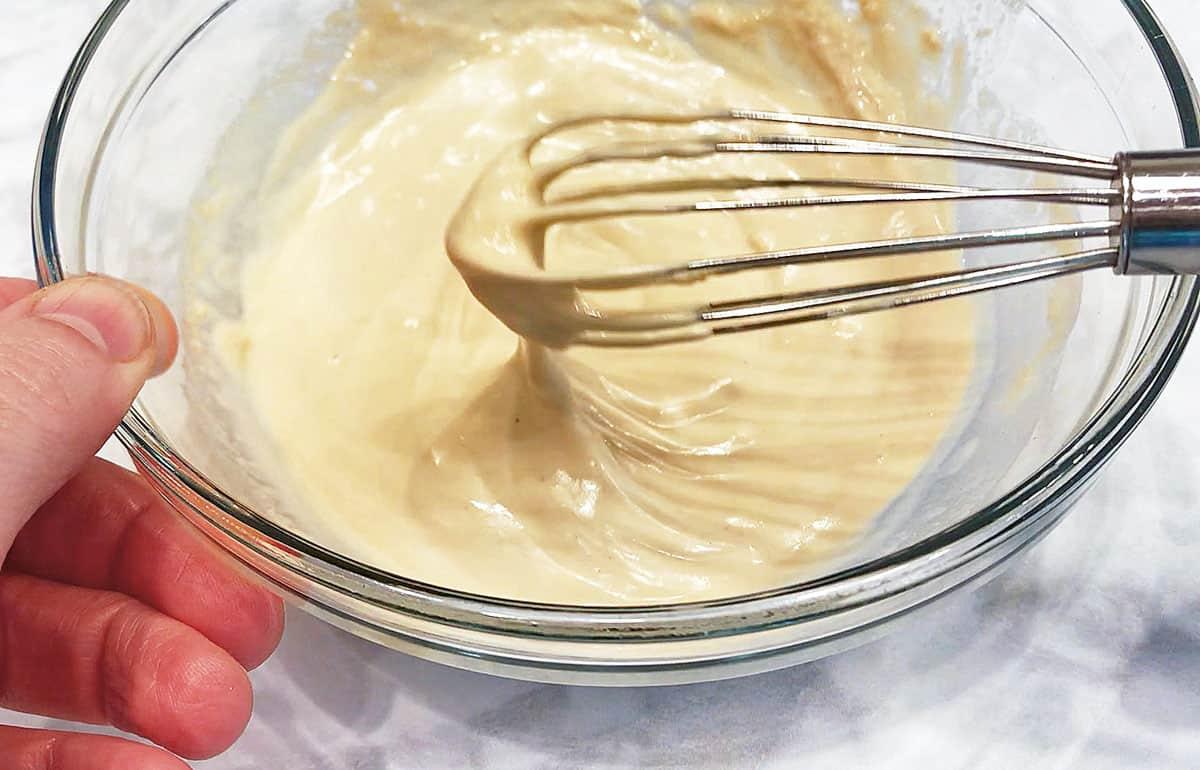 close up of sesame tahini dressing being whisked in a bowl