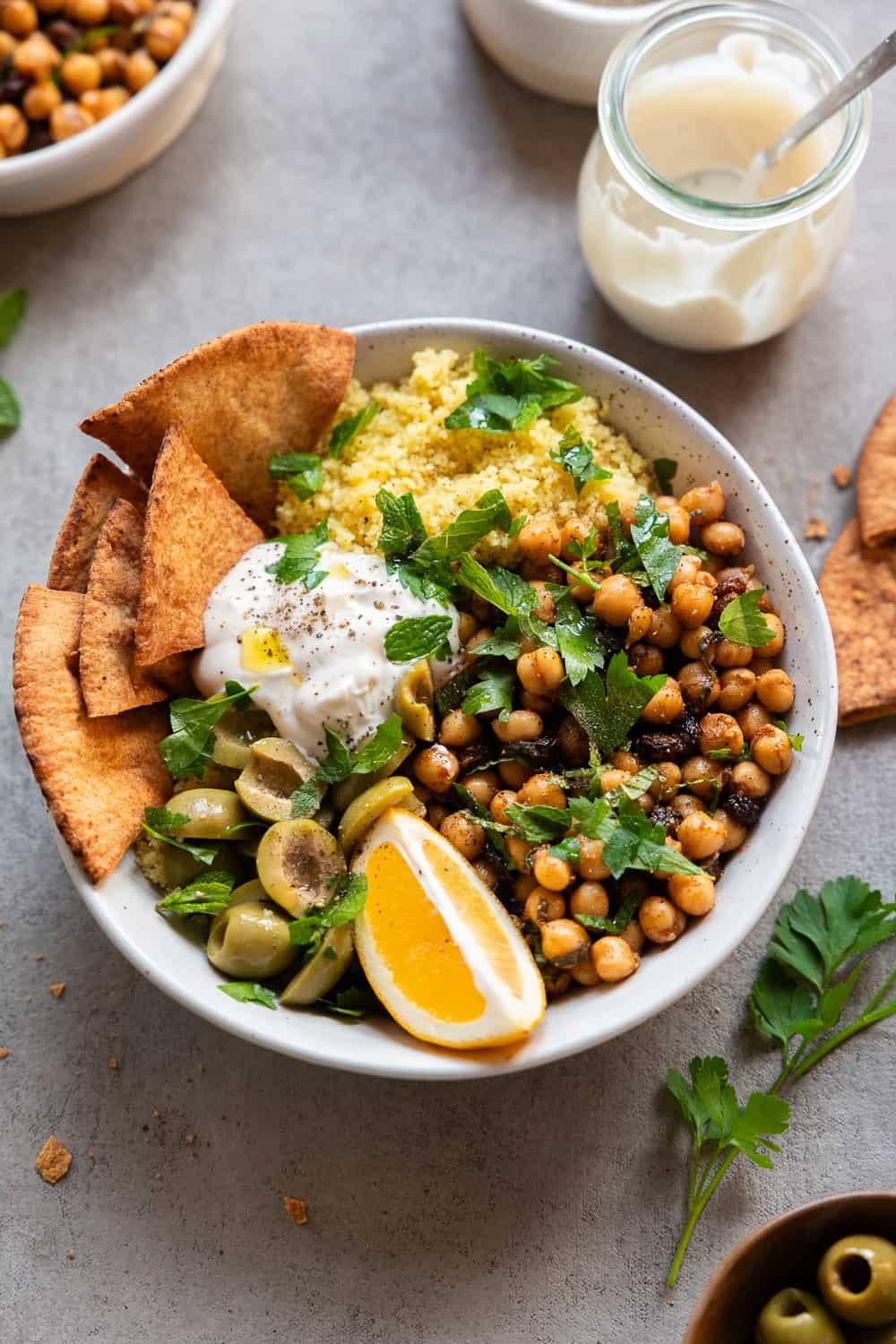 Overhead shot of a colorful Moroccan spiced chickpea bowl being assembled