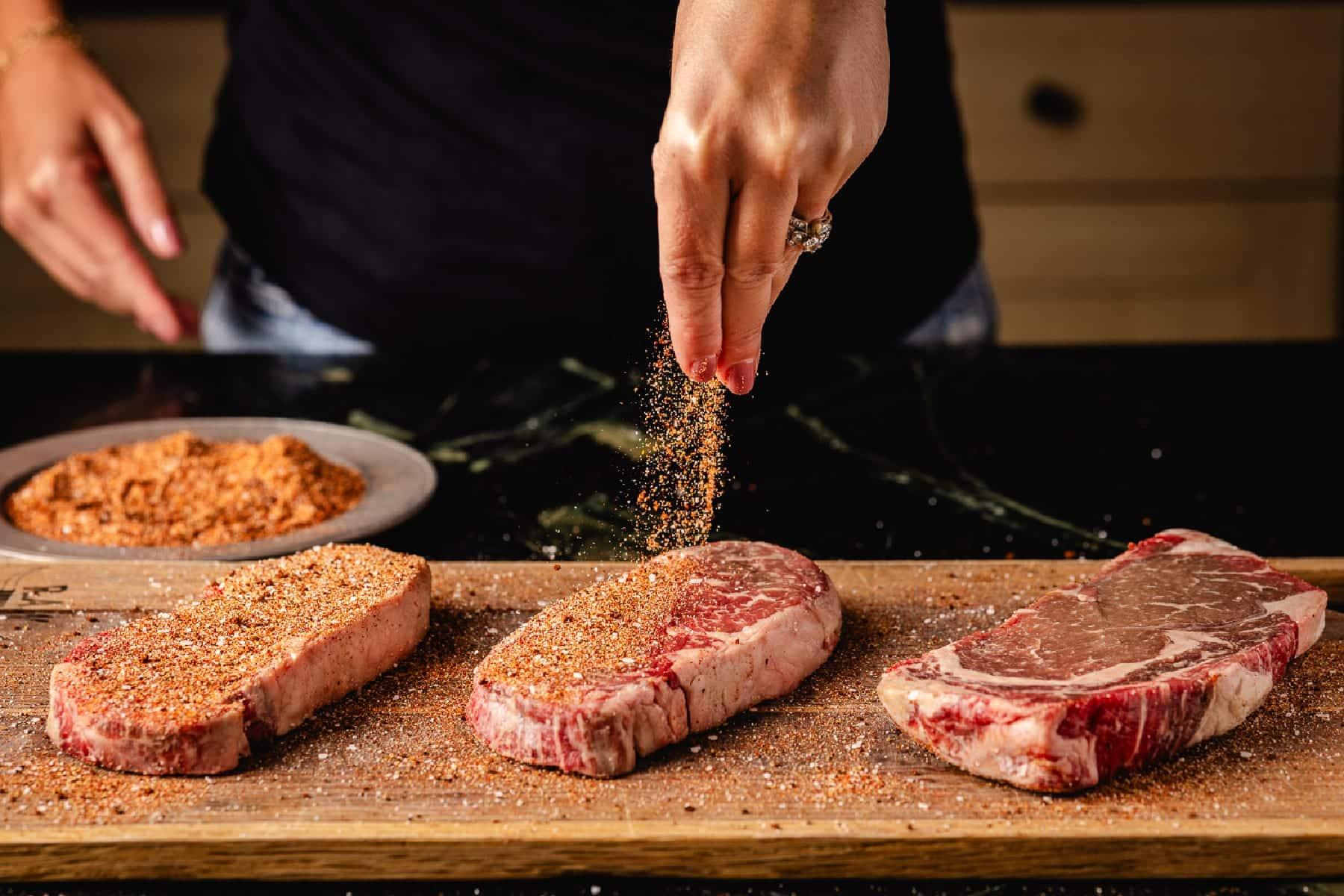 coffee rub being applied to raw steak