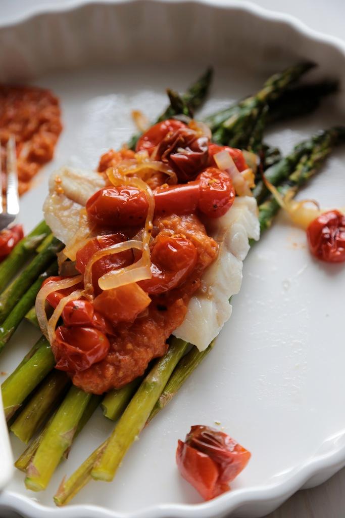 Grilled cod topped with roasted red pepper sauce, served with a side of asparagus